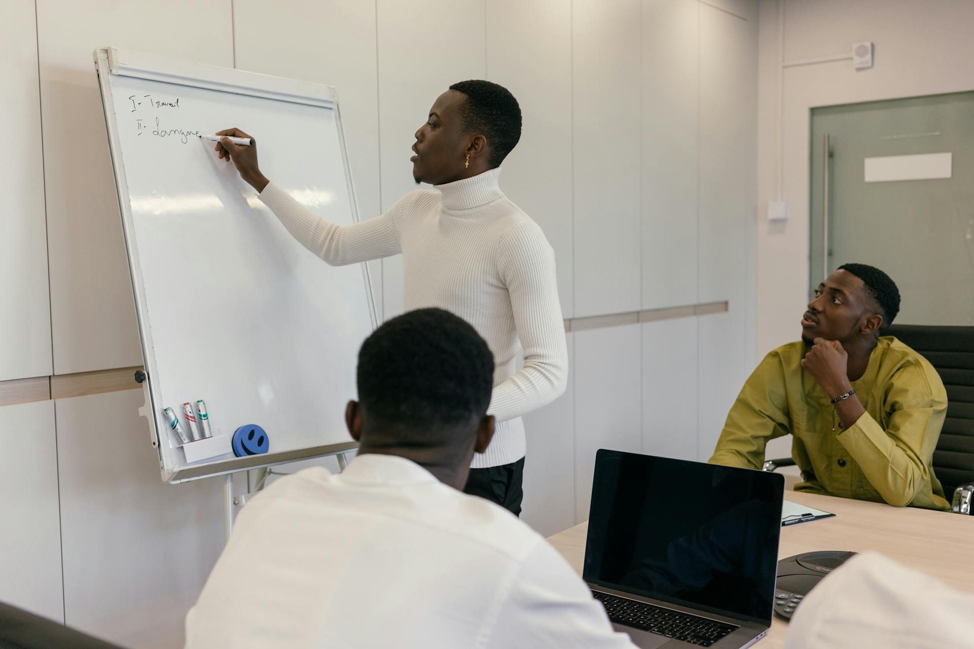 Three colleagues engaged in a brainstorming session using a whiteboard in a modern office.