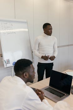 Professional meeting with colleagues using a laptop and whiteboard.