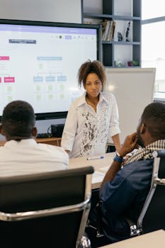 Business meeting with team discussing strategy, led by a professional woman in an office.