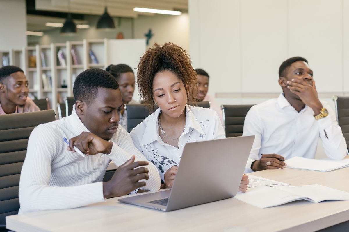 Young professionals work together around a laptop at a shared table