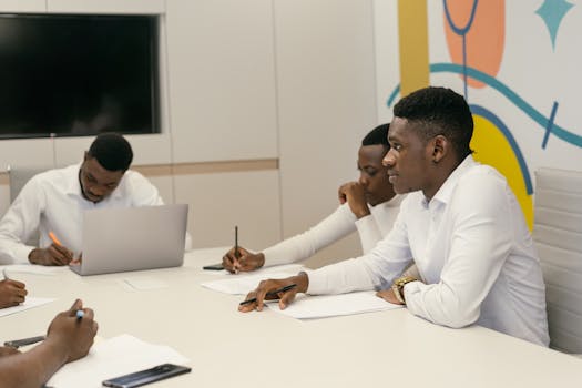 Colleagues engage in a professional meeting in a modern conference room, discussing work projects.