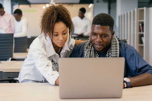Free Two colleagues working together on a laptop in a contemporary office environment. Stock Photo