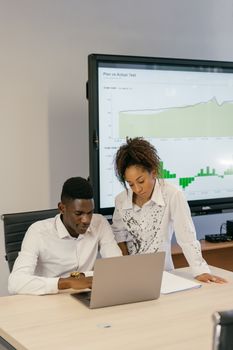 Colleagues collaborate on data analysis in a modern office setting with graphs on display.