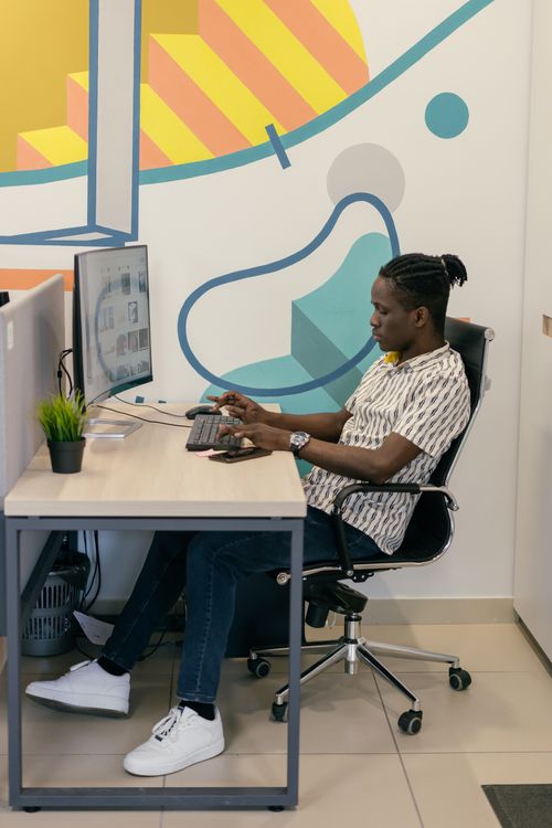Free A man working at a computer in a modern office setting, focused on his tasks Stock Photo