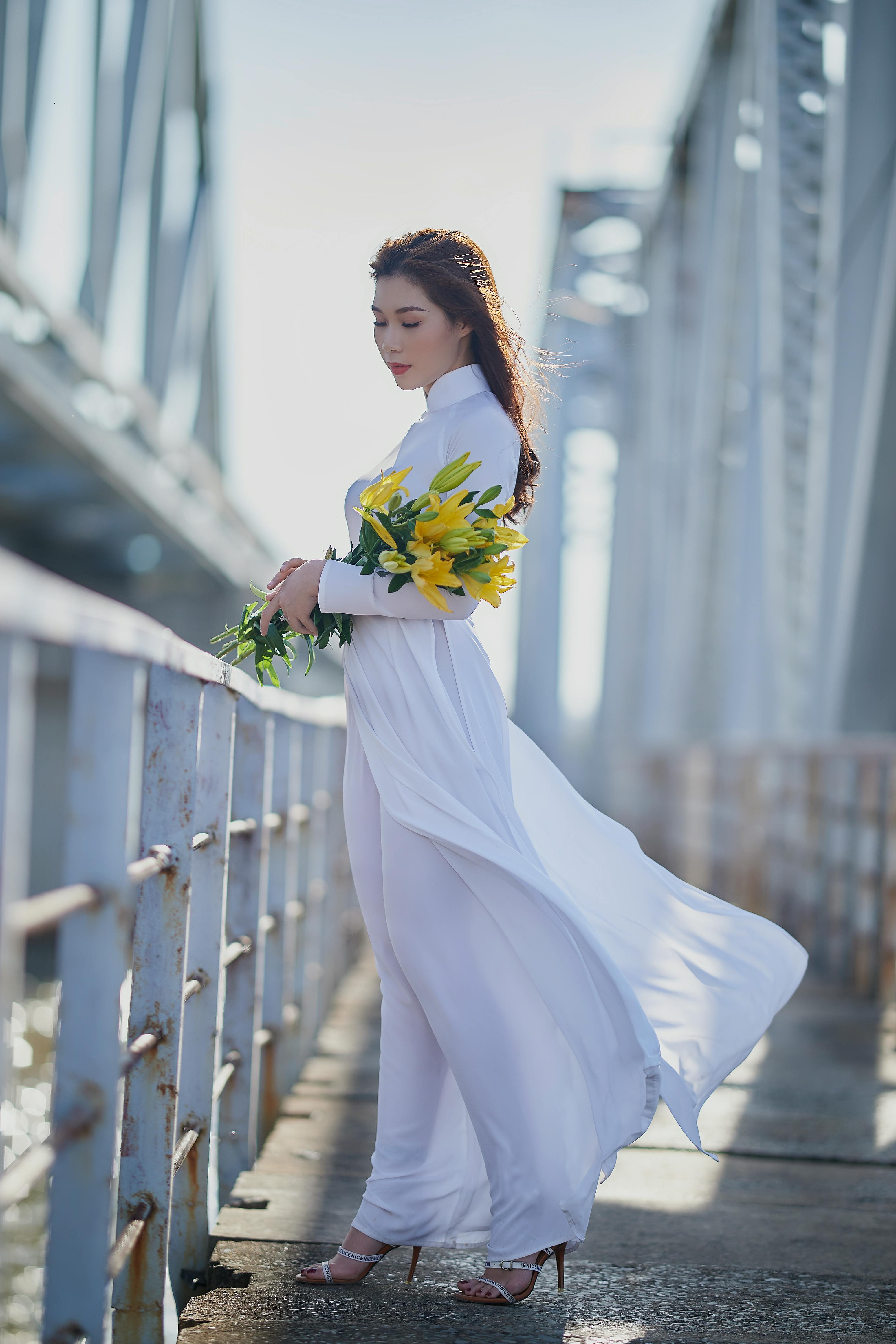 a woman in an ao dai holding flowers