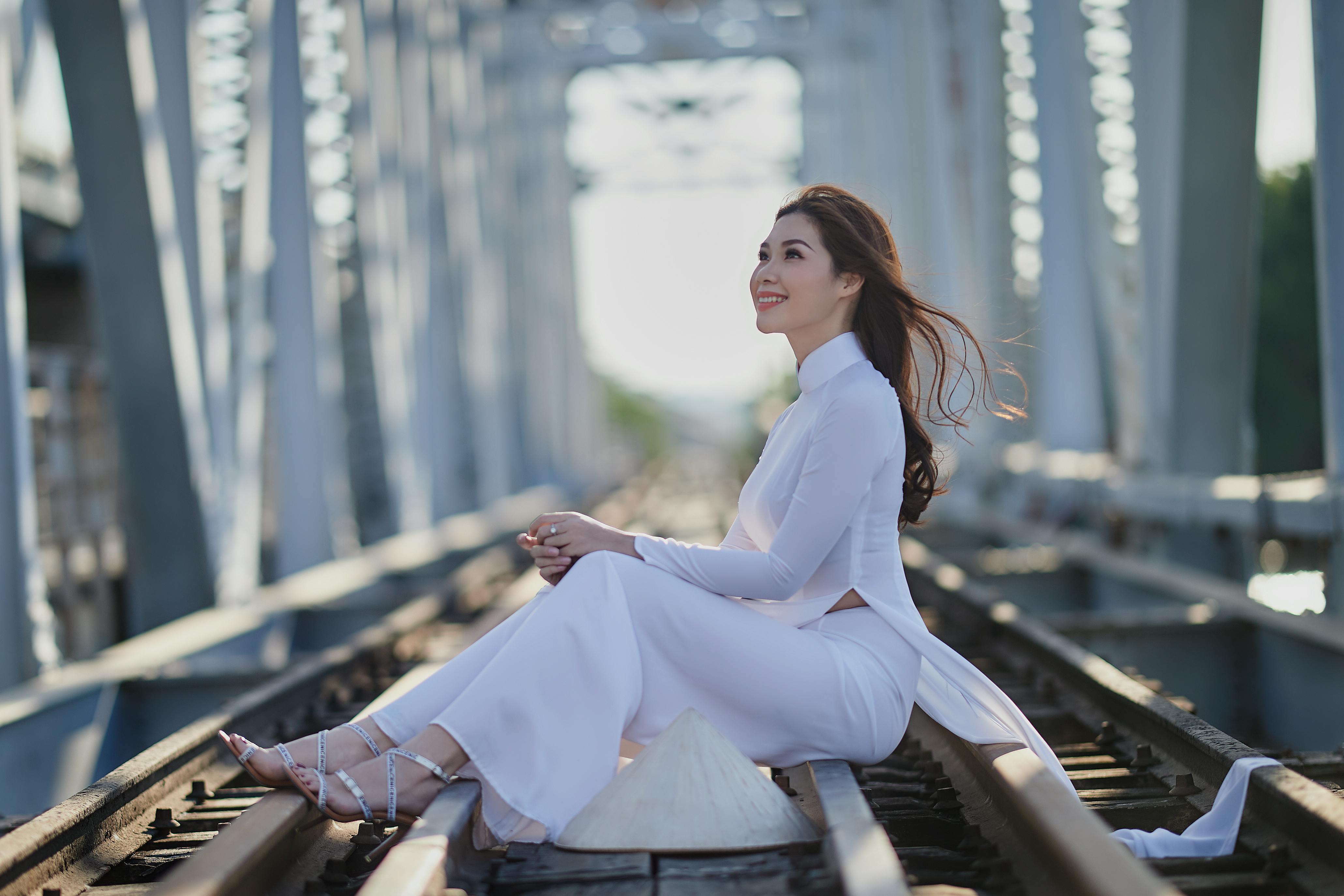 a woman in an ao dai sitting on a railway