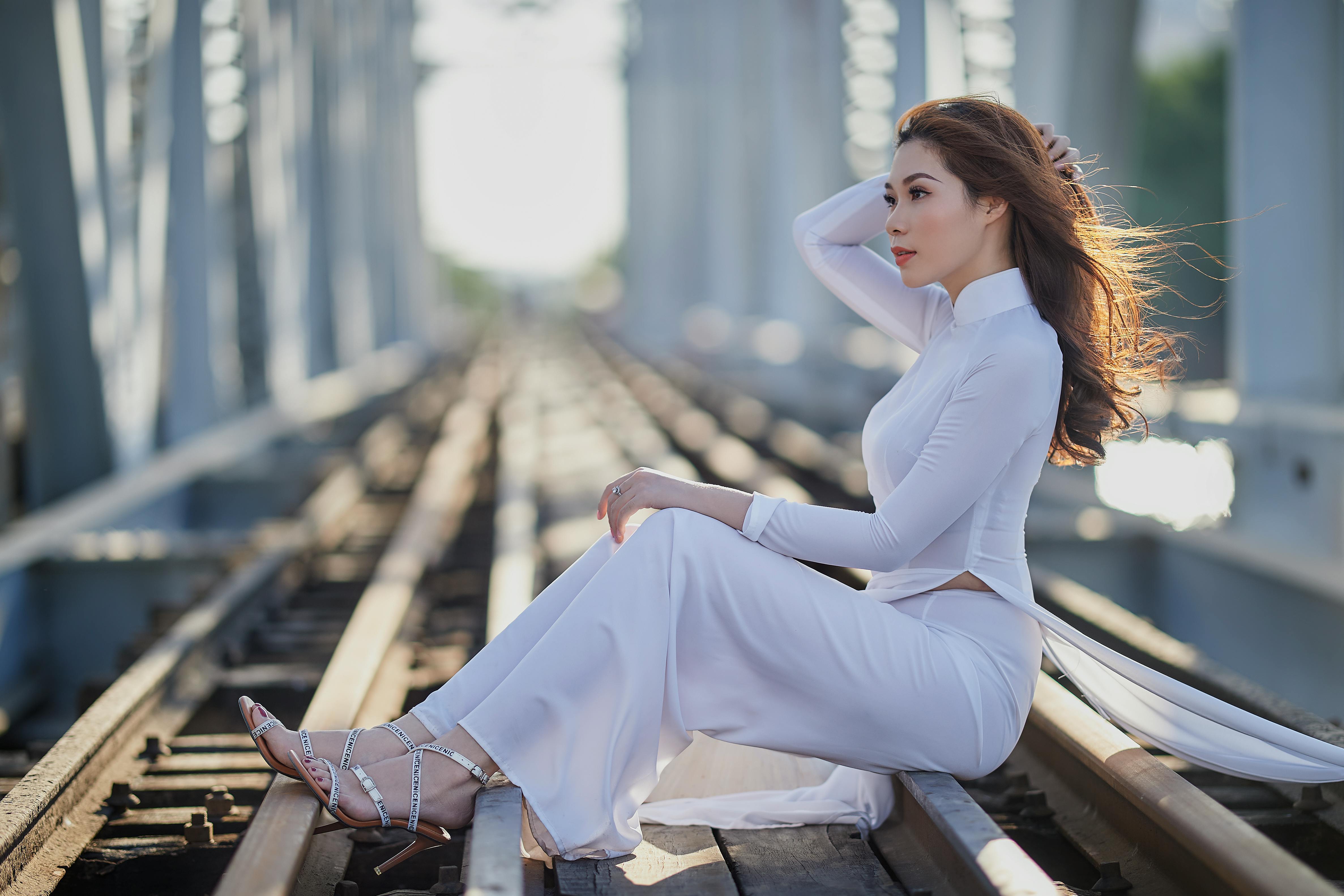 woman in traditional wear sitting on rail track