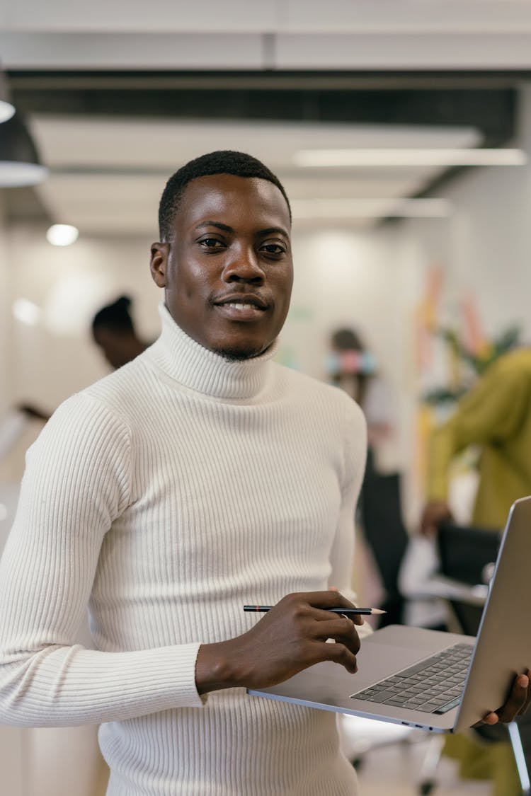 Man In A White Turtleneck Shirt Holding A Laptop