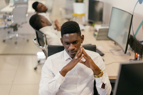 Free Young man intensely focused at his workstation in a modern office setting, thinking deeply. Stock Photo