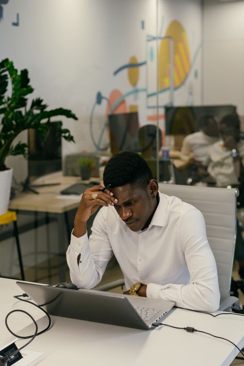 Free Businessman in white shirt focused on laptop work in modern office setting with vibrant decor. Stock Photo