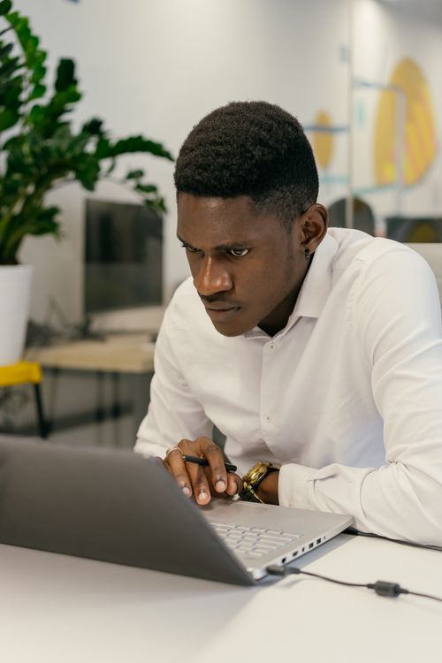 Free Professional adult working on a laptop in a modern, plant-filled office space. Stock Photo