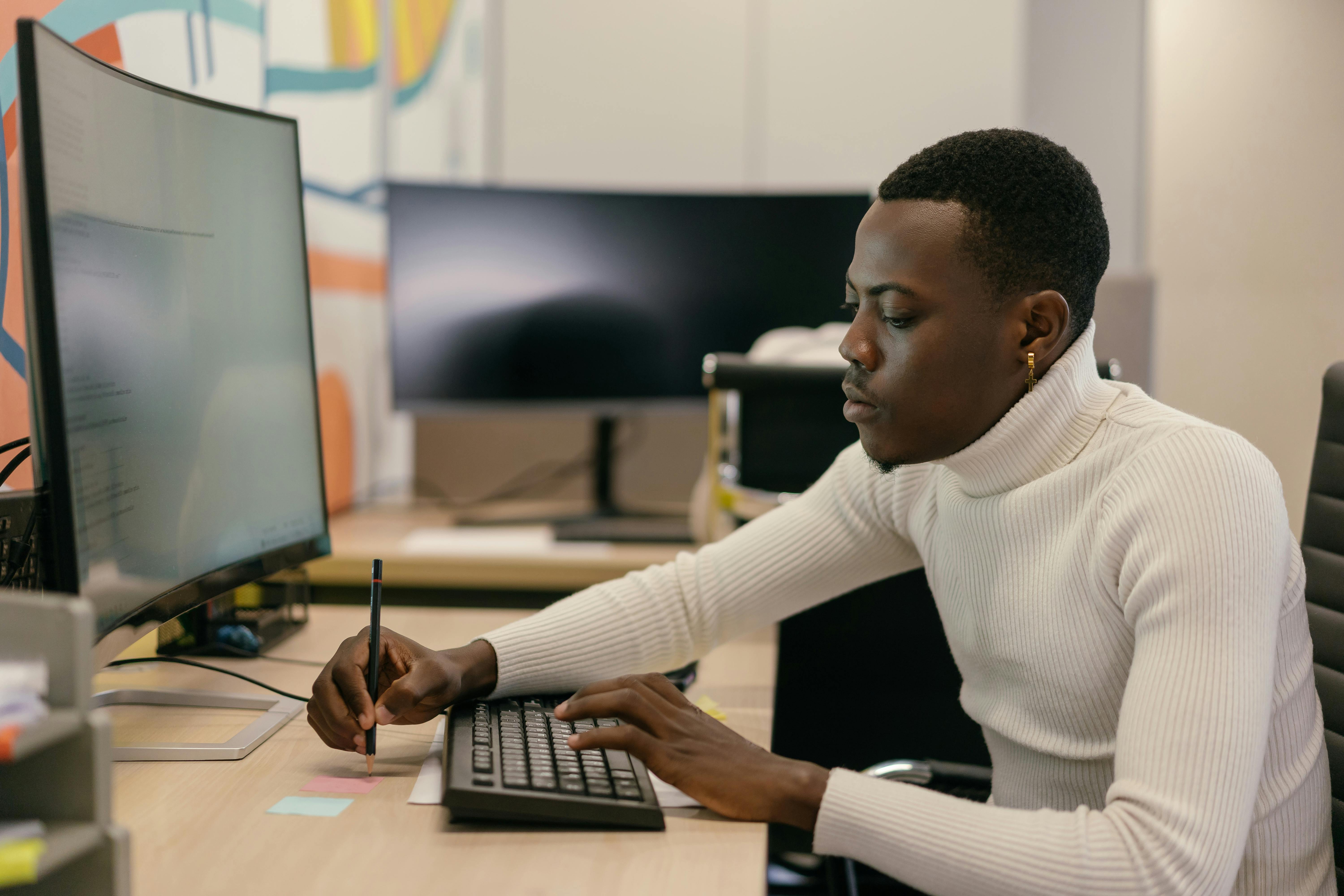 man in white sweater using a computer at work