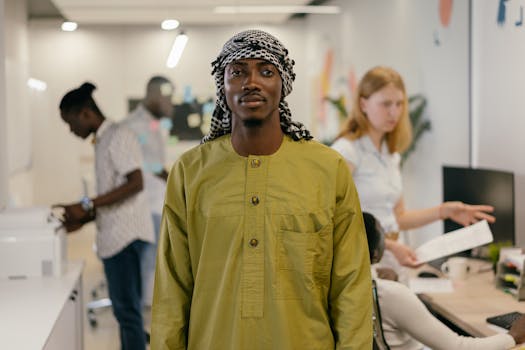 A man in traditional green attire and kaffiyeh in a contemporary office setting.