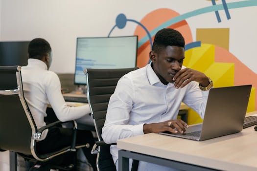 Two African American men working intently at desks in a vibrant modern office setting.