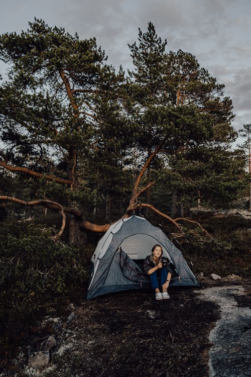Free A woman enjoys a quiet moment by her tent in the picturesque Ruskeala forest. Stock Photo