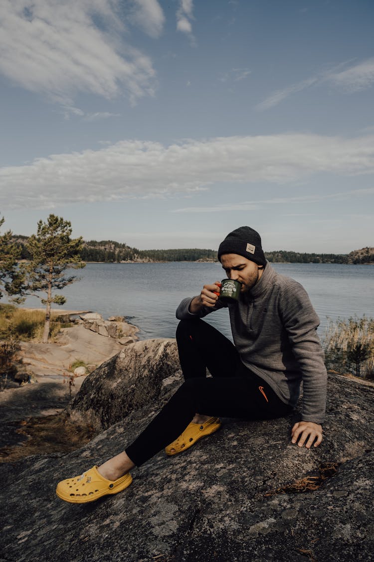 Man Sitting On The Ground While Drinking From A Cup