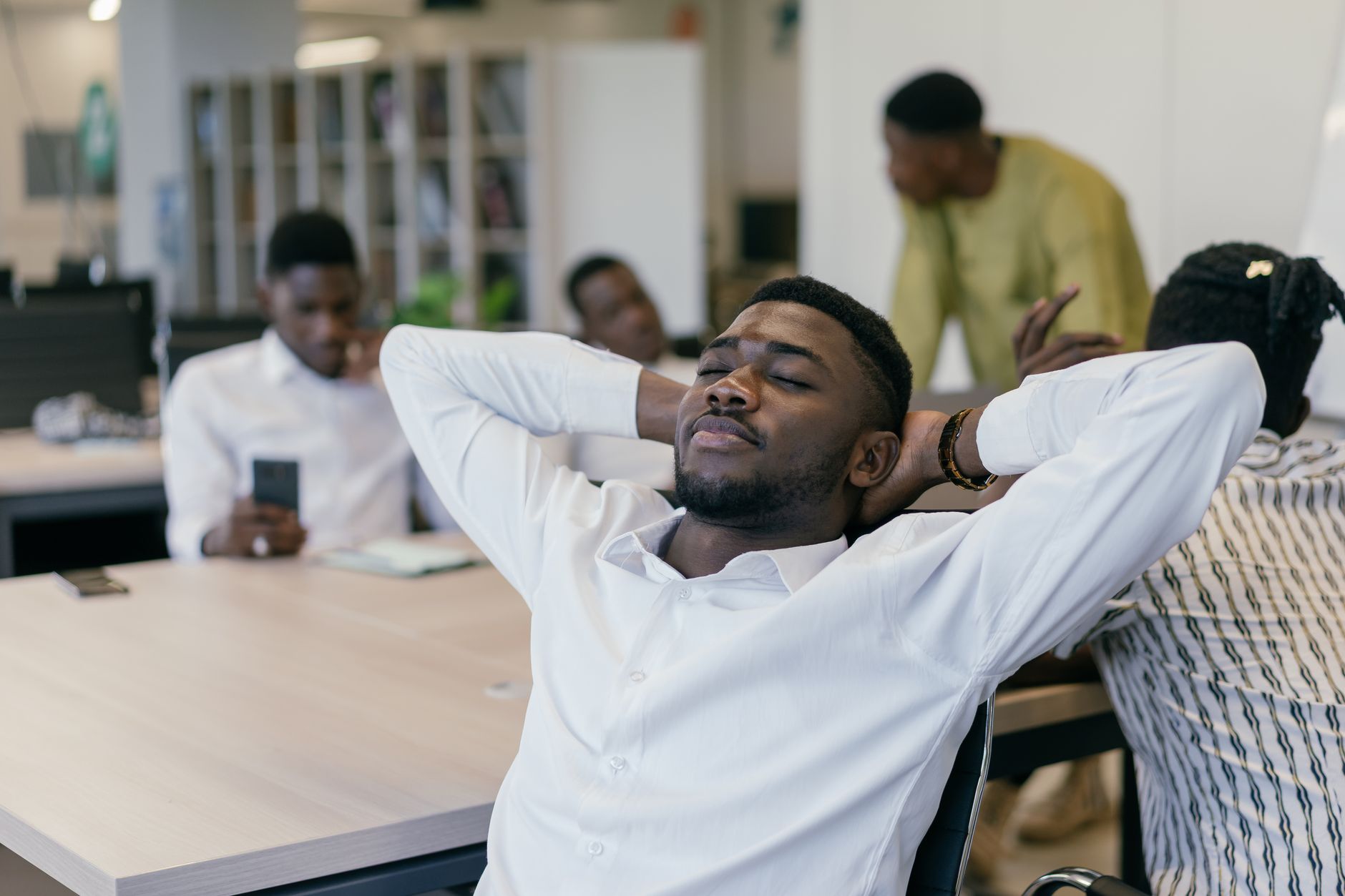Office workers take a break, relaxing at desks in an open plan space.