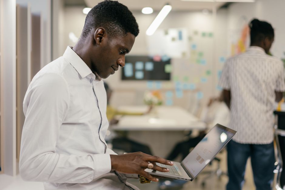 Man in white shirt focused on laptop in a creative office space.