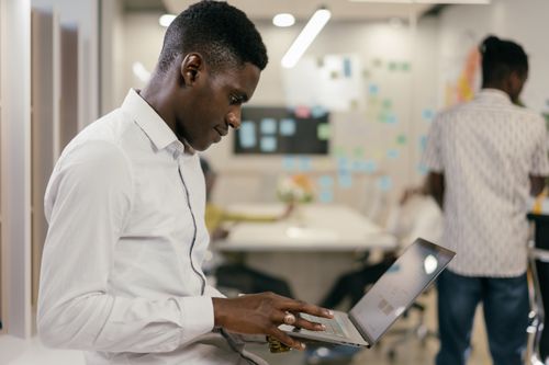 Free Man in white shirt focused on laptop in a creative office space. Stock Photo