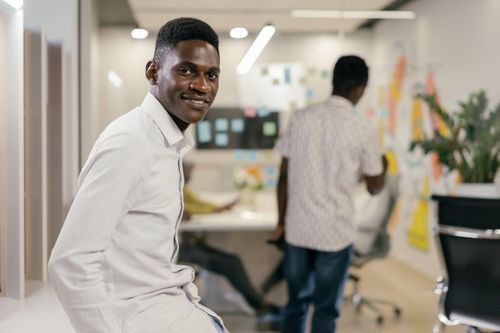 Free A smiling African American man in a modern office setting, embodying workplace positivity. Stock Photo