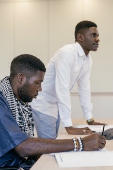 Two men engaged in a business discussion at an office desk, working collaboratively.