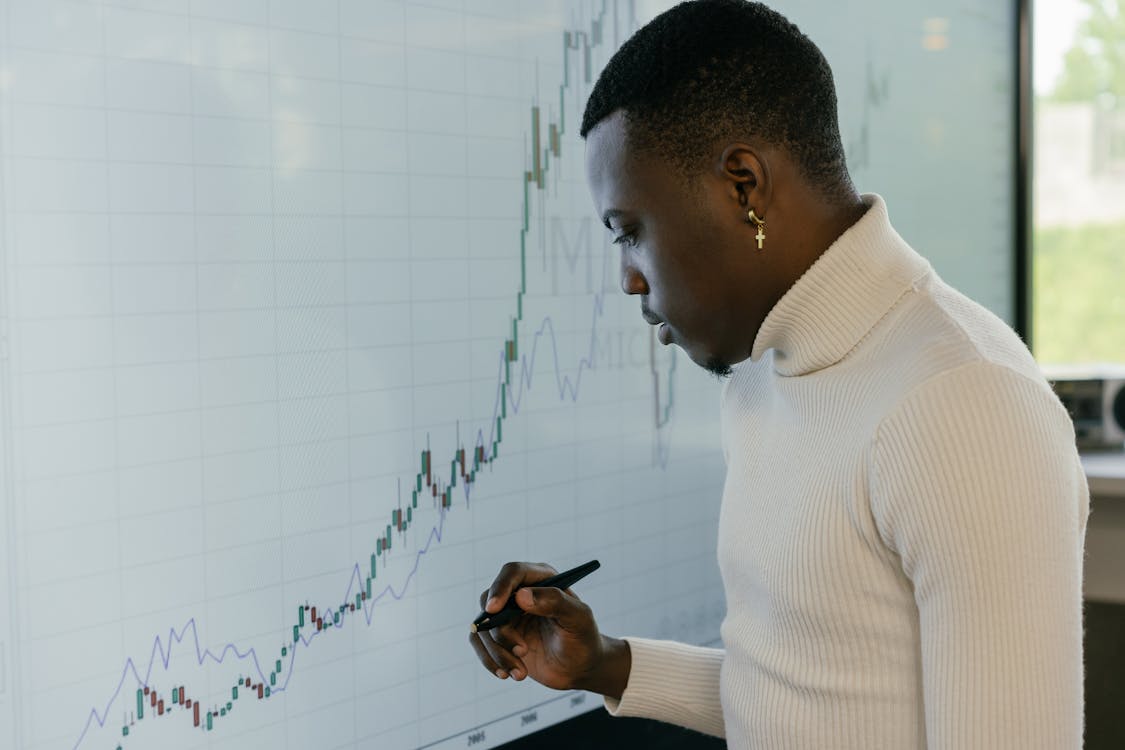 A Man in a Turtleneck Sweater Looking at a Graph · Free Stock Photo