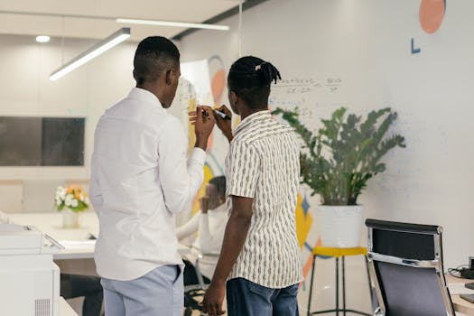 Colleagues brainstorming and writing on a glass board in modern office.