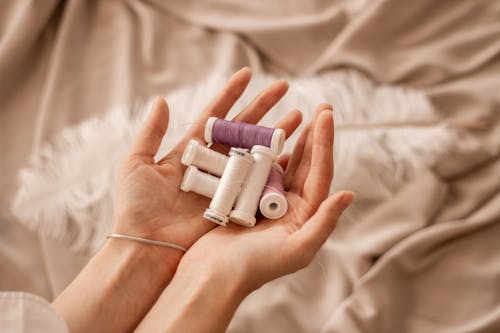 White and Purple Sewing Threads on a Persons Hand