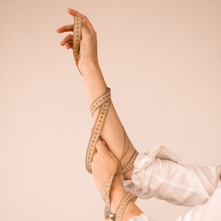 Measuring tape wound around a raised arm. Photo by Анастасия Триббиани on Pexels