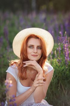Charming portrait of a woman posing with a hat in a lavender field, showcasing a serene summer vibe.