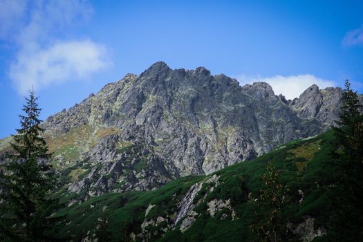 Capture the serene beauty of a rocky mountain peak under a clear blue sky.