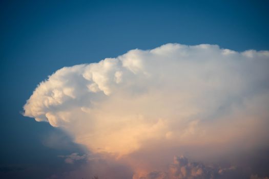 Majestic Cumulonimbus cloud formation against a serene blue sky at sunset.