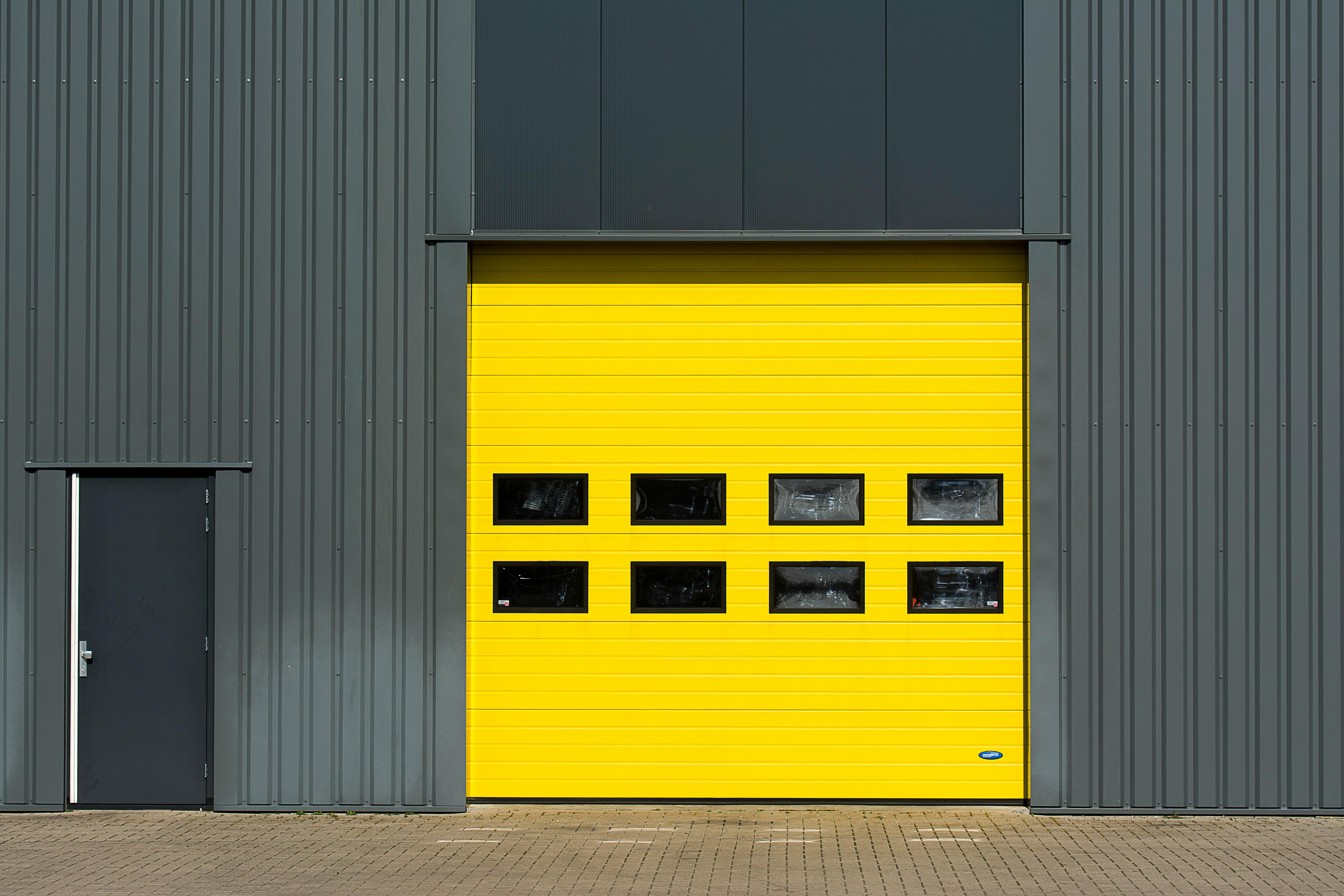 A sleek industrial structure featuring a vibrant yellow garage door for architectural interest.