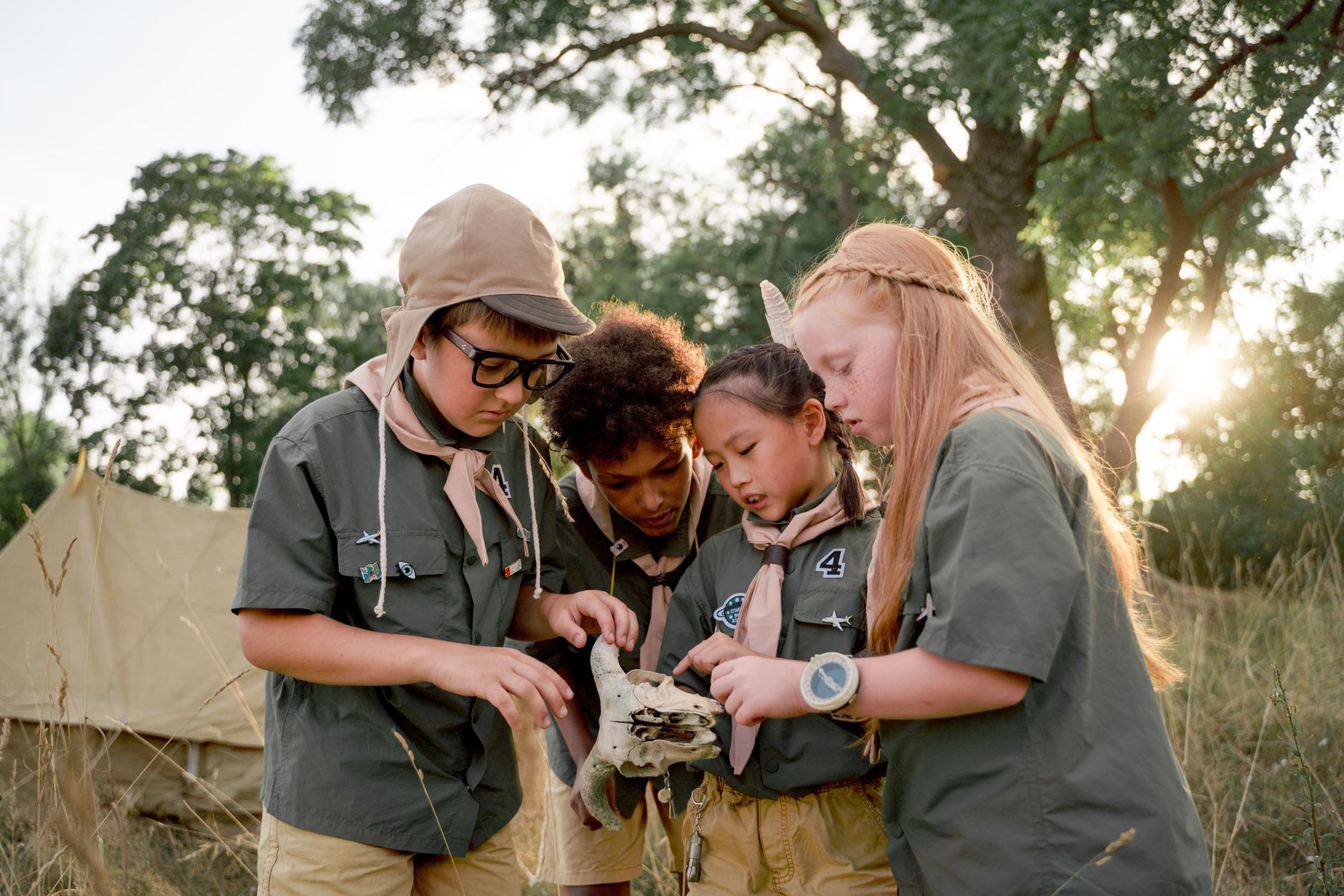 A group of diverse scouts examining an animal skull outdoors, fostering exploration and teamwork.