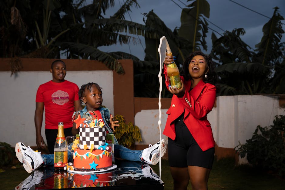 A backyard birthday party with colorful banners, folding chairs, and a homemade cake laid out on a table surrounded by smiling children.. Photo taken by Felix Adams