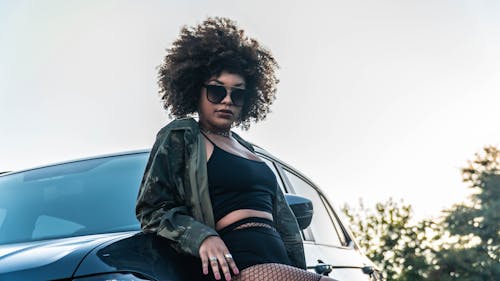 Curly Haired Woman in Camouflage Jacket Leaning on a Car