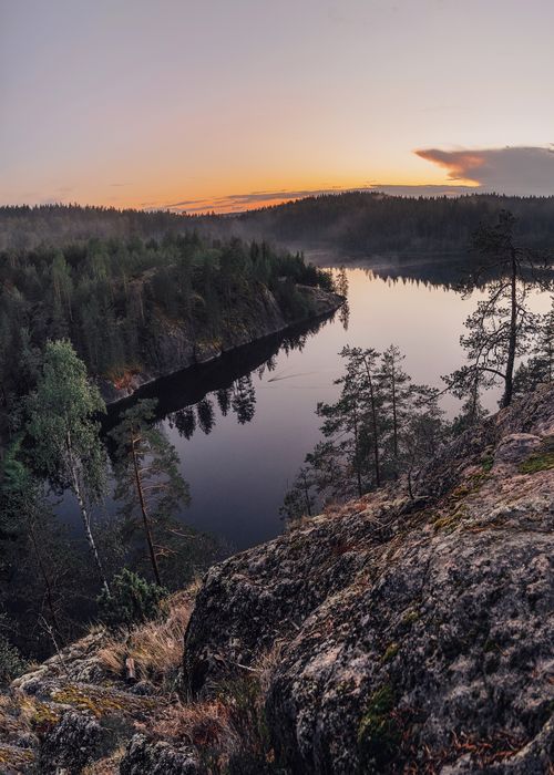 Free A beautiful view of a serene river and dense forest beneath a vibrant sunset sky. Stock Photo