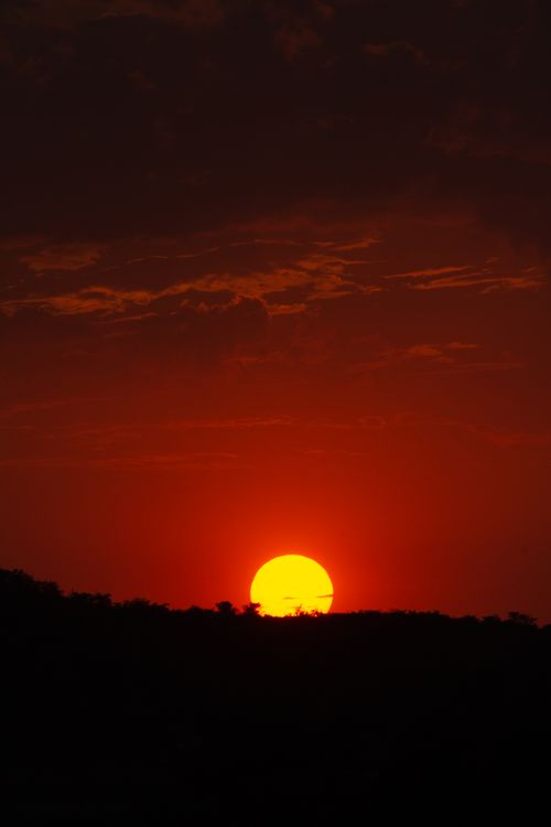 Free Beautiful sunset with a vibrant red sky over a silhouetted horizon creating a mesmerizing twilight scene. Stock Photo