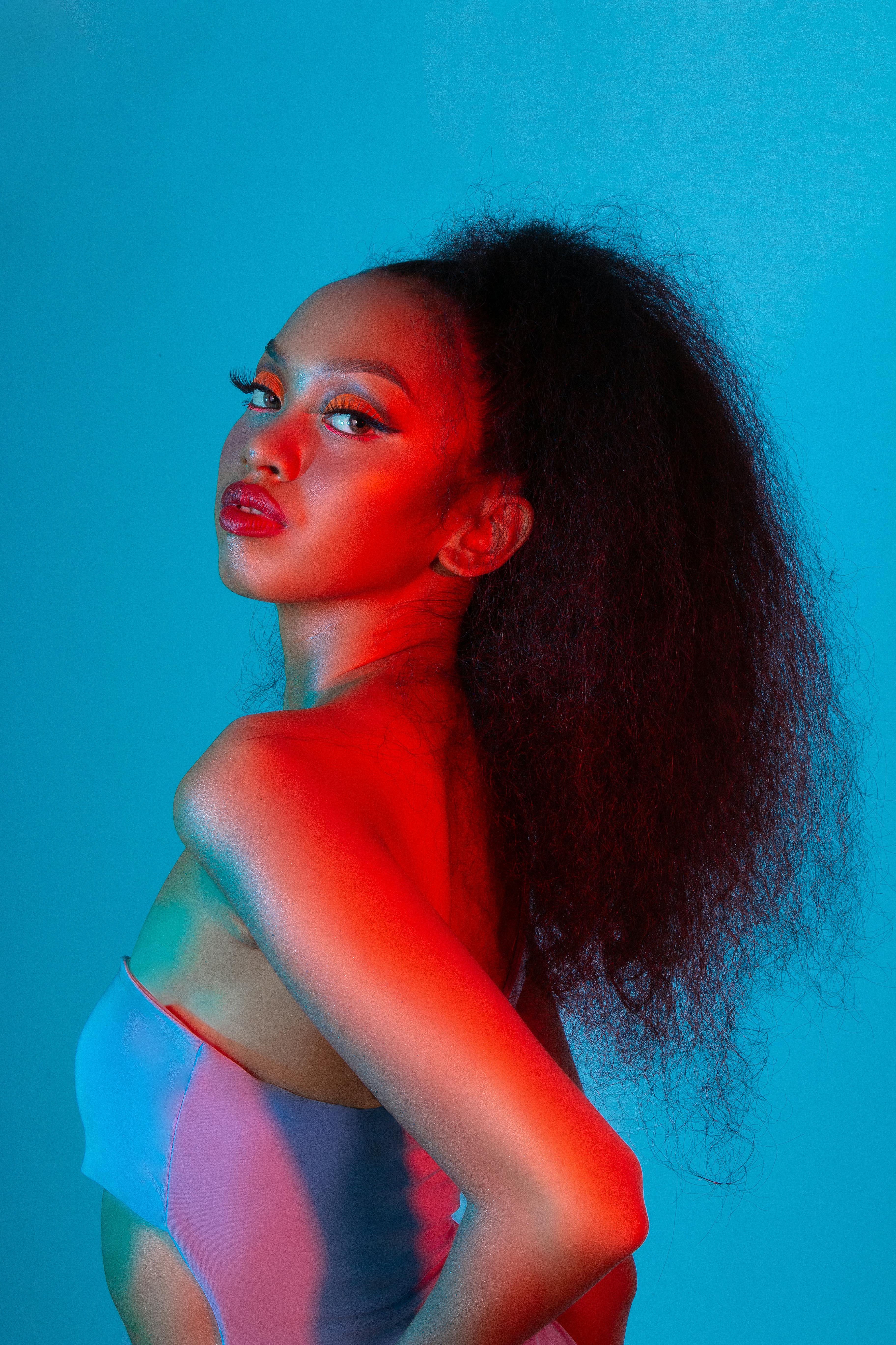 迷人的肖像的一个女人摆出时髦的对一个充满活力的蓝色背景