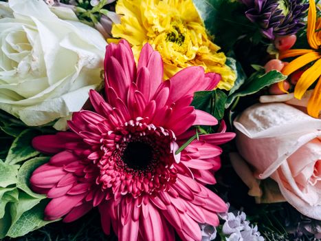 Close-up of a vibrant mixed bouquet with daisies, roses, and gerbera in pink, yellow, and white.