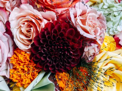 Close-up of a colorful floral arrangement featuring roses, dahlias, and marigolds.