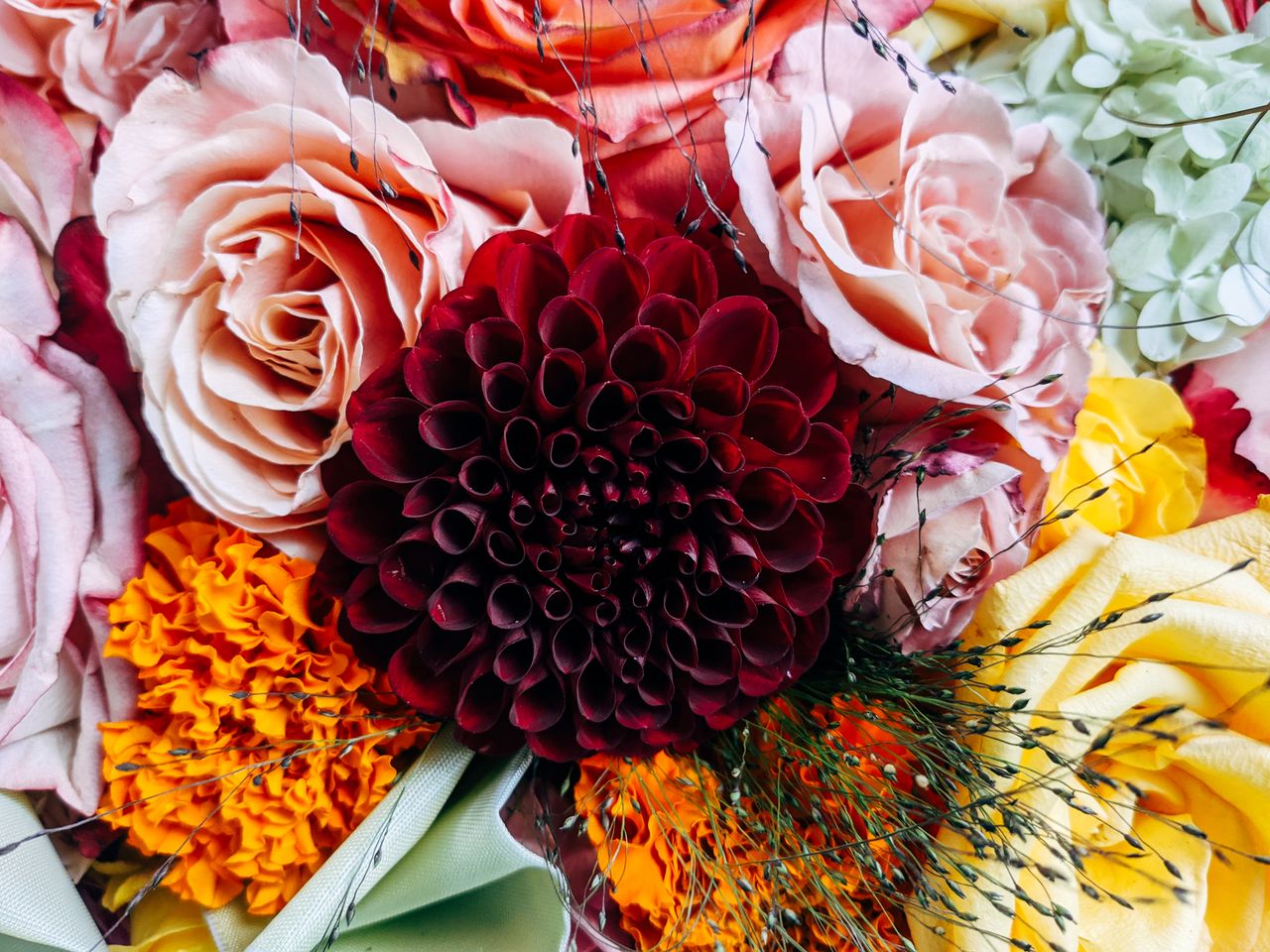close up of a colorful floral arrangement featuring roses dahlias and