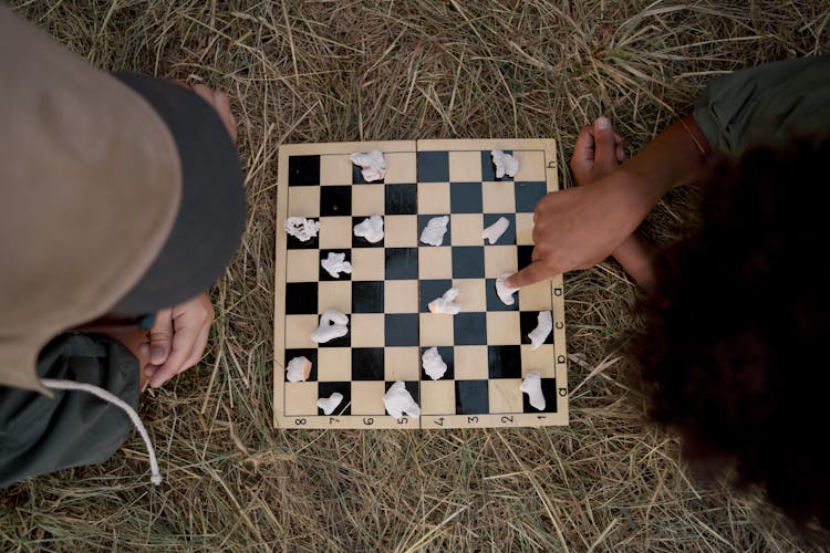 People Playing Board Game On Brown Grass