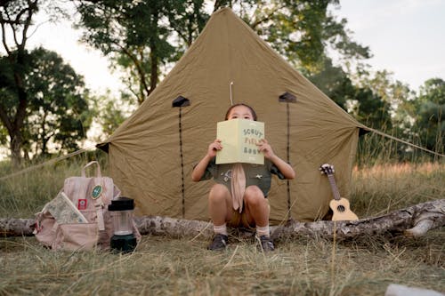 Boy Holding a Scout Book in Front of a Tent 