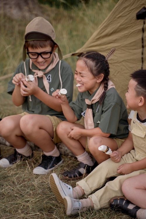 Free Group of children laughing and enjoying marshmallows by a tent during a camping trip. Stock Photo