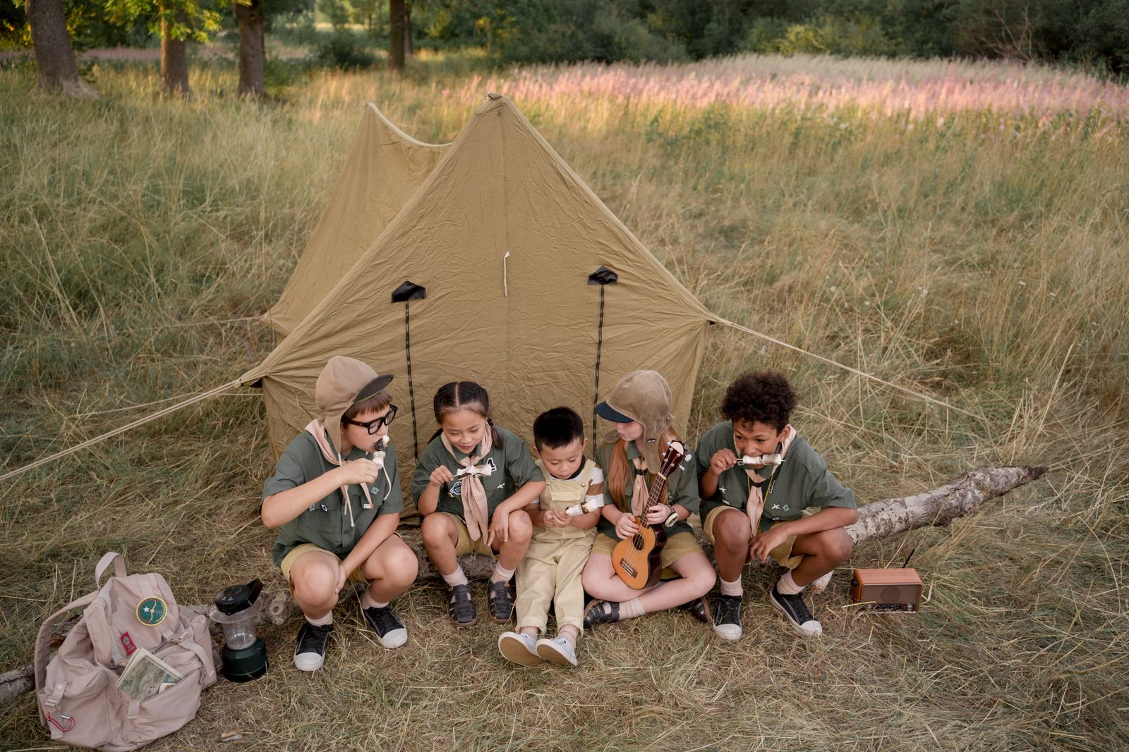 Little campers sitting by a tent with a ukulele