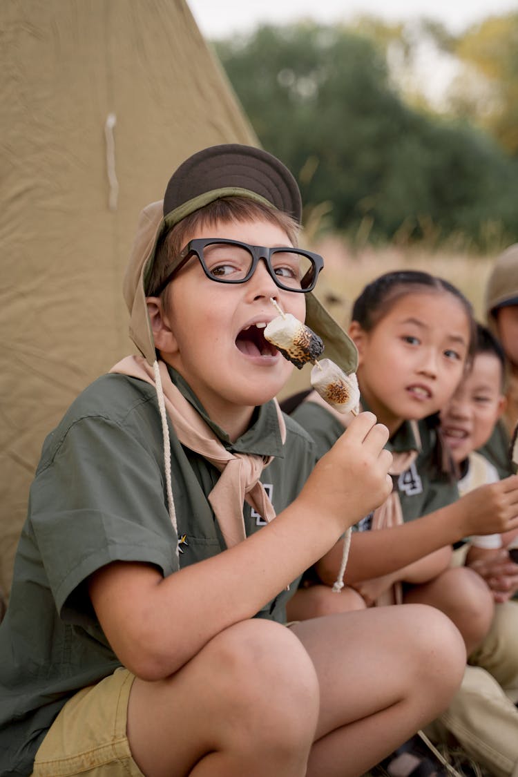 A Boy Eating Marshmallows On Stick 