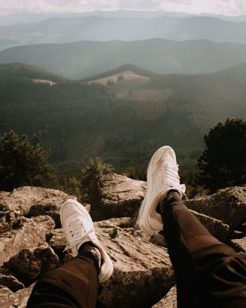Free Man relaxing on a rocky mountain peak enjoying nature's view. Stock Photo