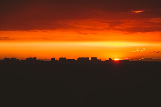 Stunning vibrant orange sunset casting silhouettes over a cityscape.