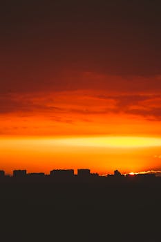 Dramatic sunset silhouette over cityscape with vivid orange sky creating a stunning view.